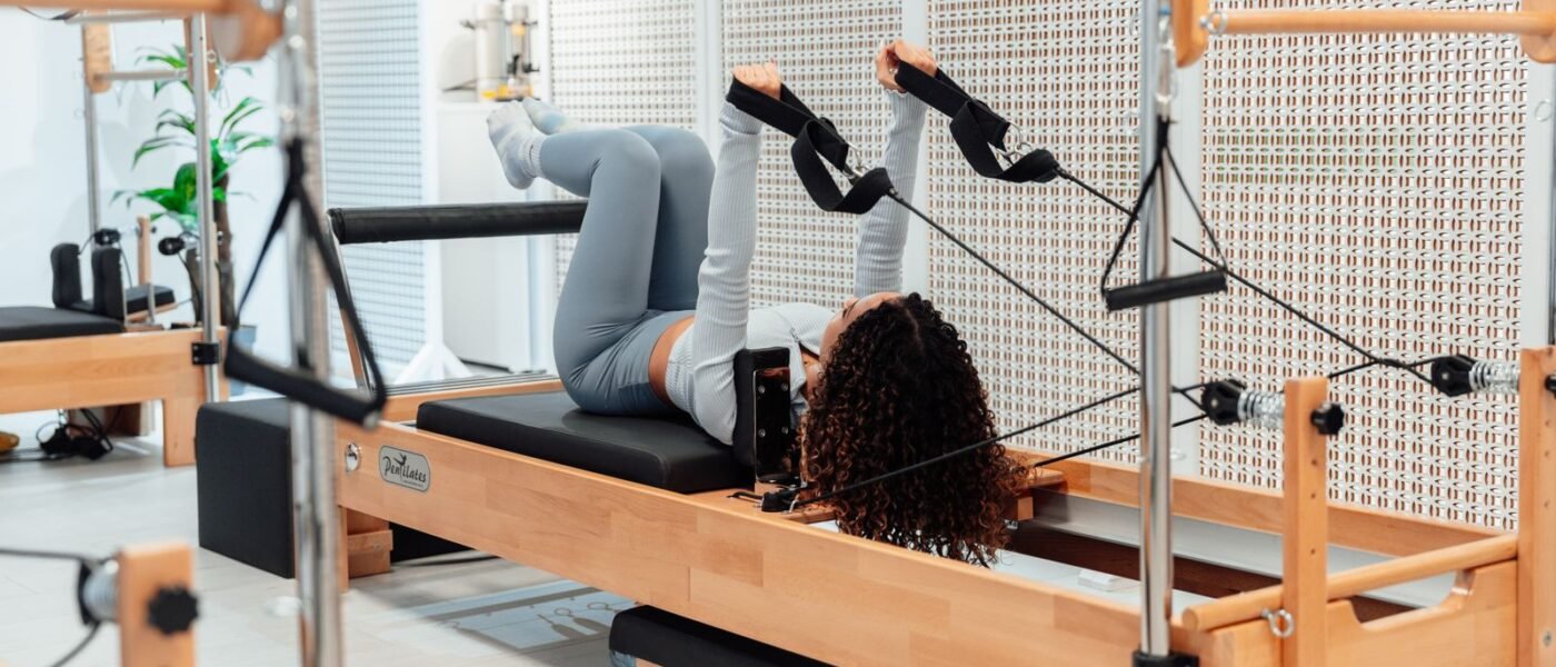 Pratiquante allongée sur un reformer en bois, les pieds dans les sangles