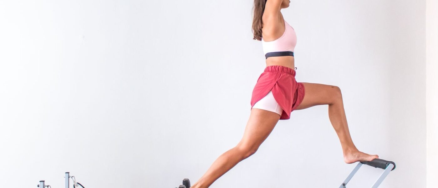 Femme en fente sur un reformer Pilates posé dans une pièce de la maison