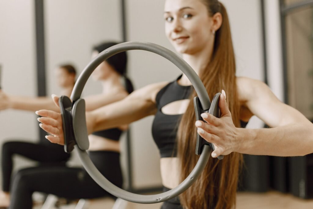 Femme réalisant un exercice de pression poitrine avec un anneau de Pilates en cours collectif