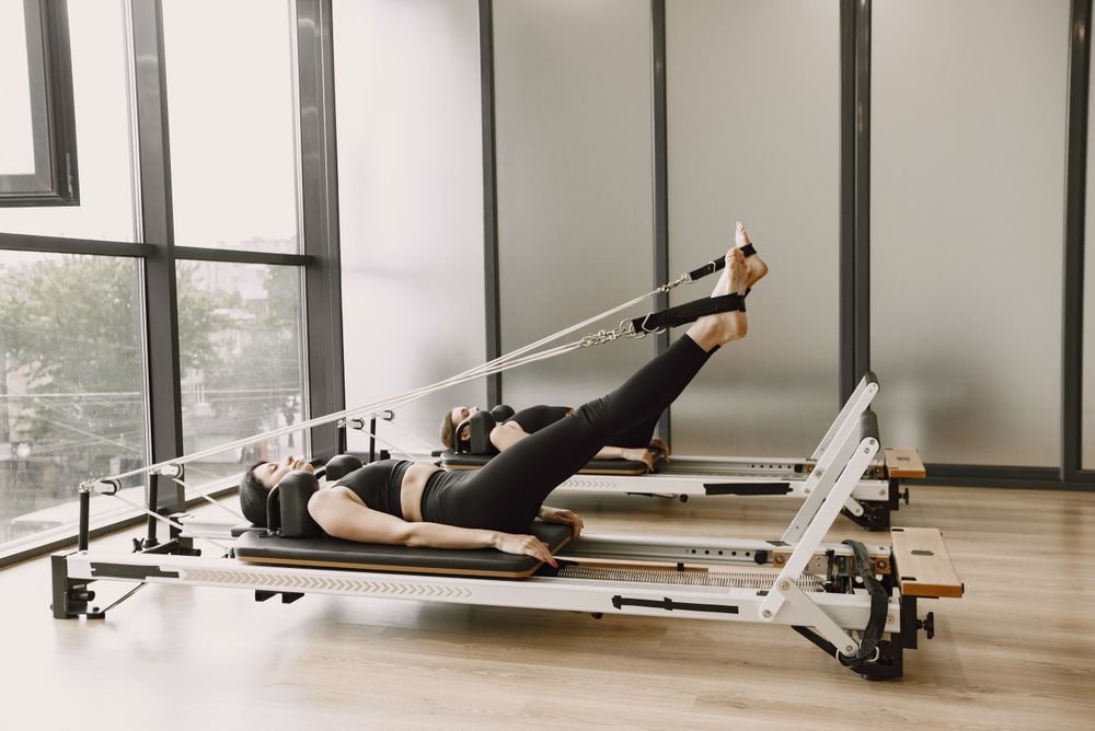 Pratiquante allongée sur un reformer Pilates dans un studio lumineux