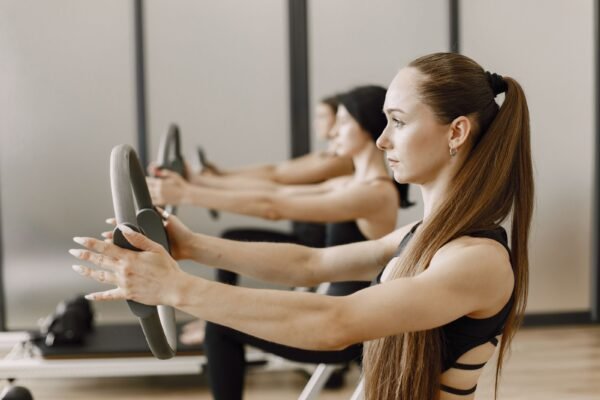 Femme réalisant un exercice de pression poitrine avec un anneau de Pilates en cours collectif
