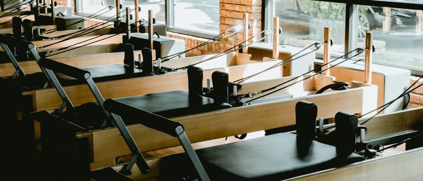 Studio de Pilates lumineux avec plusieurs reformers alignés devant de grandes fenêtres