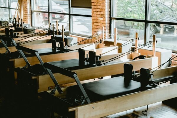 Studio de Pilates lumineux avec plusieurs reformers alignés devant de grandes fenêtres