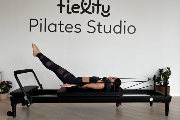 Femme pendant une séance de Pilates sur un reformer dans un studio moderne et lumineux